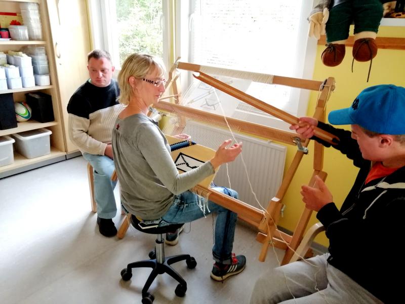 Heilerziehungspflegerin Mandy Weißhuber mit den Beschäftigten Mario und Kolja am Webstuhl